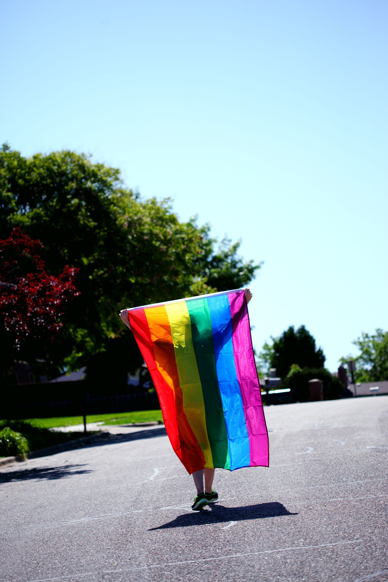 A person proudly holding a rainbow Pride flag on a sunny South Florida neighborhood street — 4 Pro Wash is an LGBTQ-friendly pressure washing company