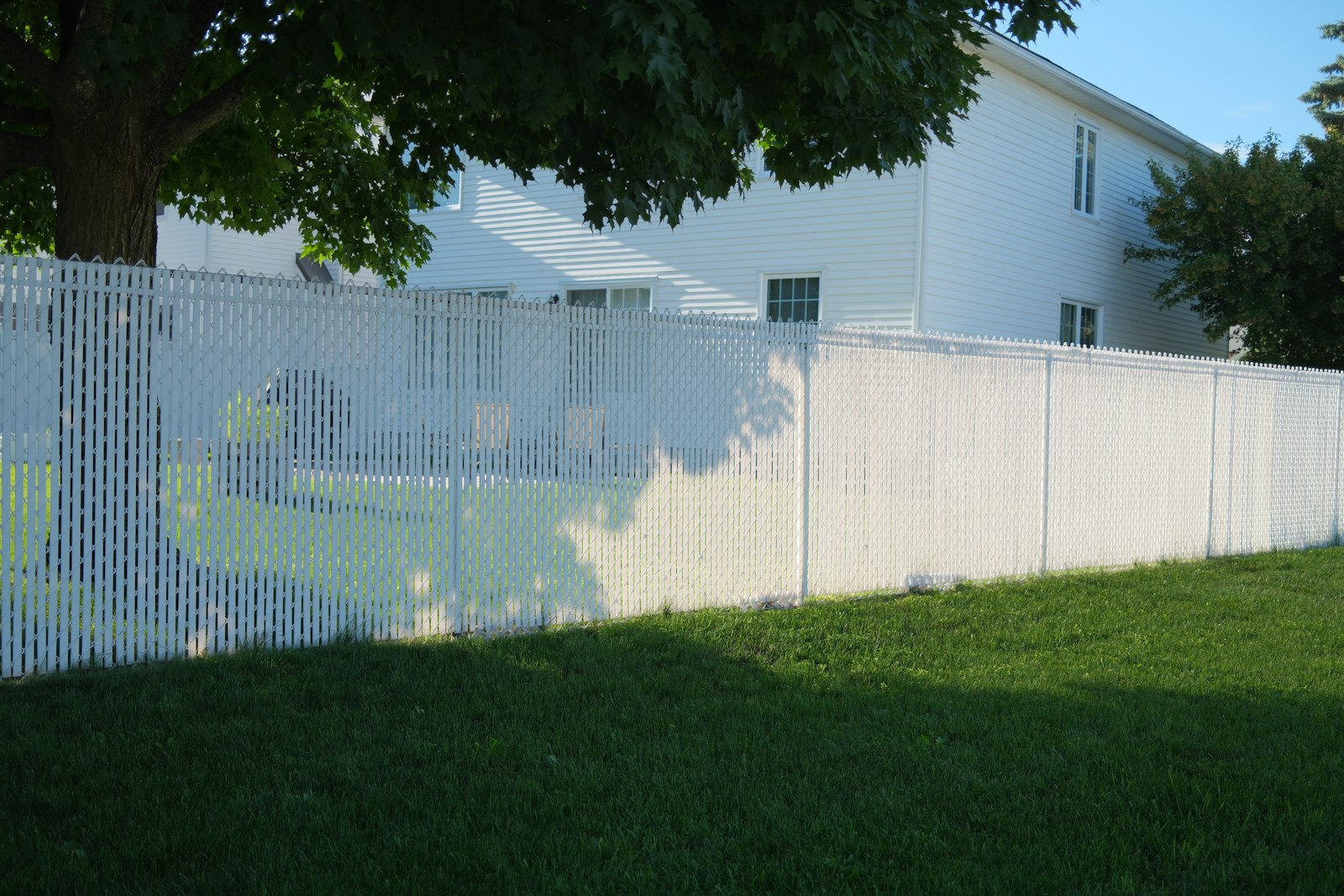 Clean white picket fence in front of a residential home